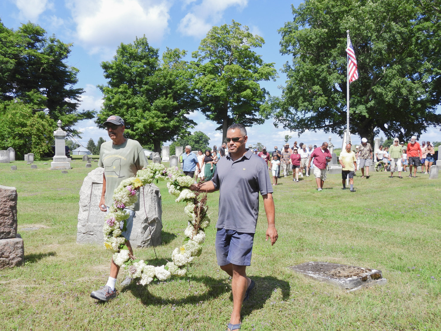 Emancipation Day Co-Chair James Corpin, left, and Jacob Donovan-Colin carry a wreath to Harriet Russell’s grave at Peterboro Cemetery as part of the annual Emancipation Day celebration on Saturday.