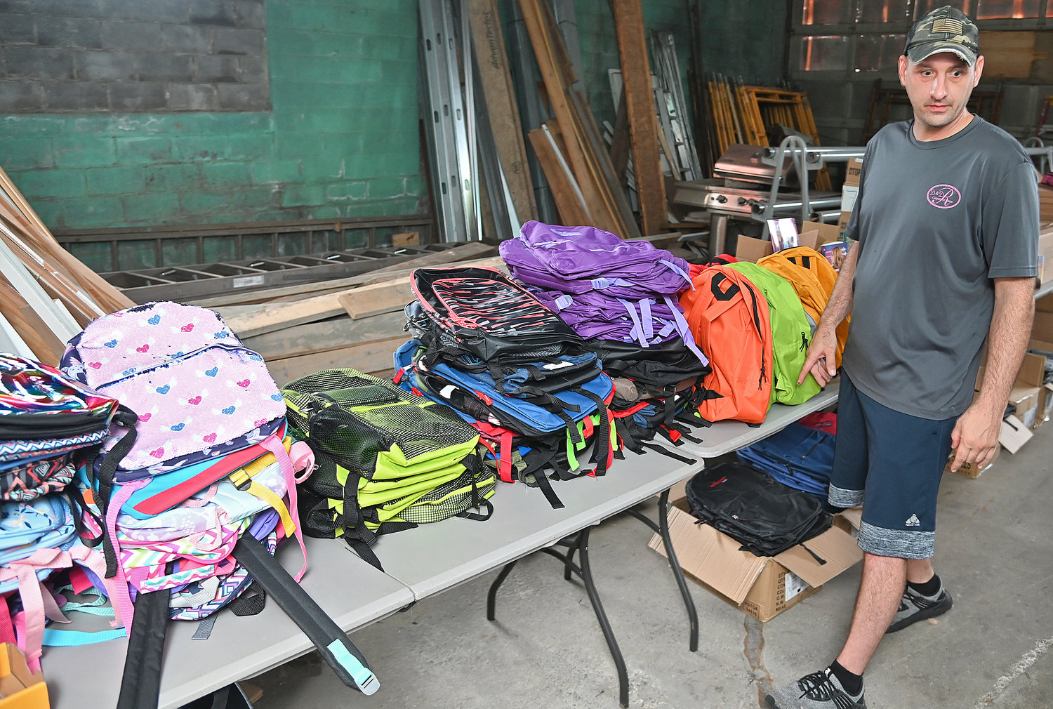 D&D Carpet owner Nazie Adolfi with just a few of the bookbags that will be given away later this month.
