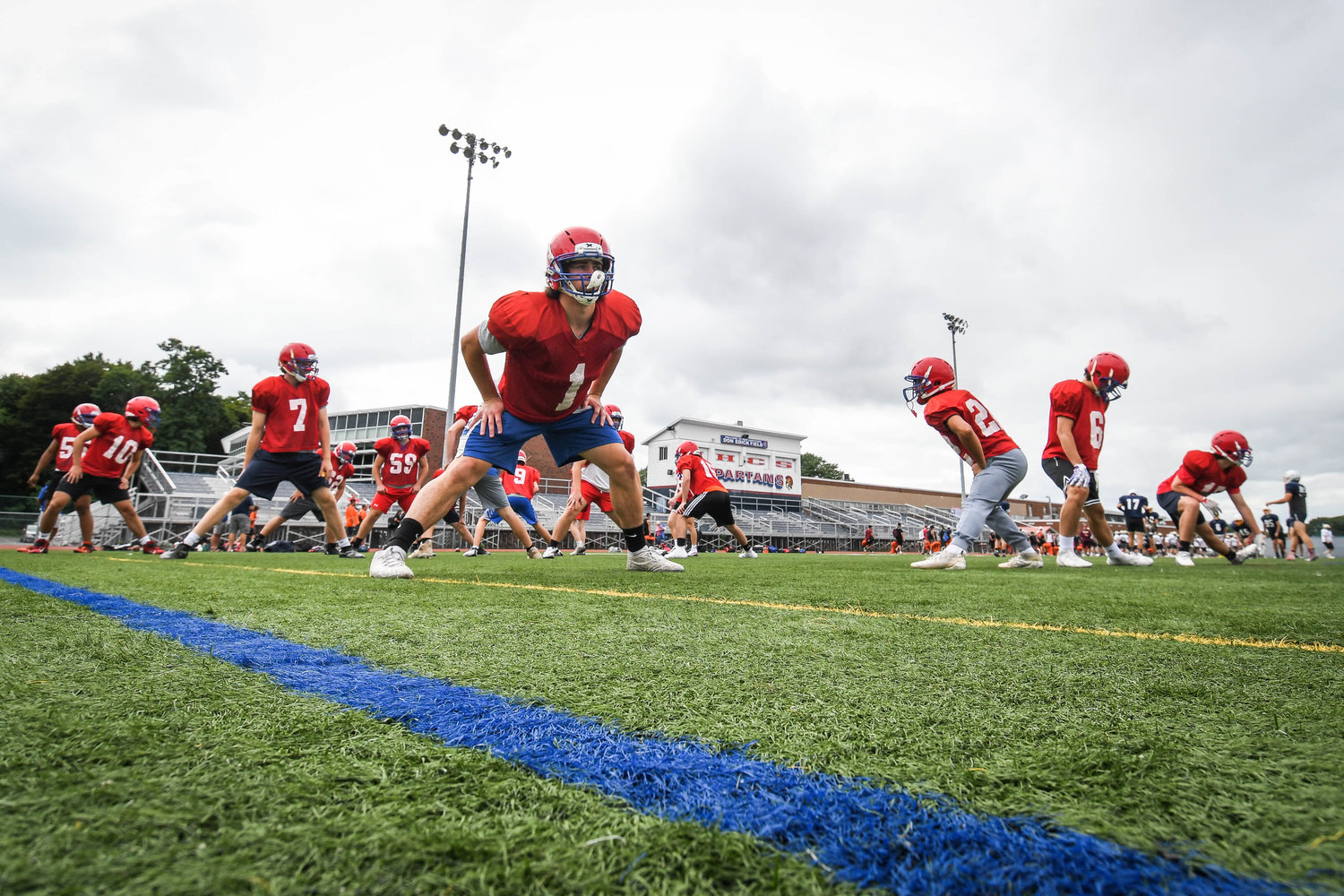 GETTING LOOSE — New Hartford football players warm up and stretch at the start of a seven-on-seven camp on Tuesday at Don Edick Field in New Hartford. The Spartans open the 2022 season on the road against Rome Free Academy at 6:30 p.m. on Friday, Sept. 2, at RFA Stadium.