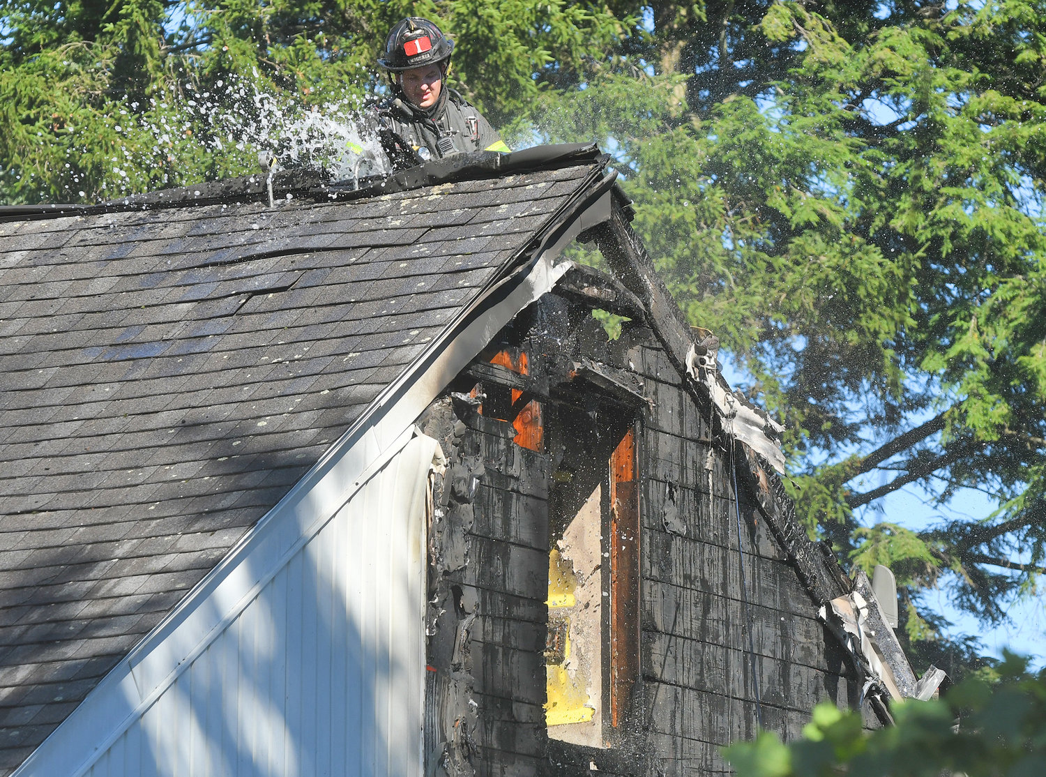 A Utica firefighter douses the peak of 408 Buchanan Road on the city's north side Thursday afternoon. According to the Utica Fire Department, an electrical issue on the outside of the residence burned up the side to the roof.
