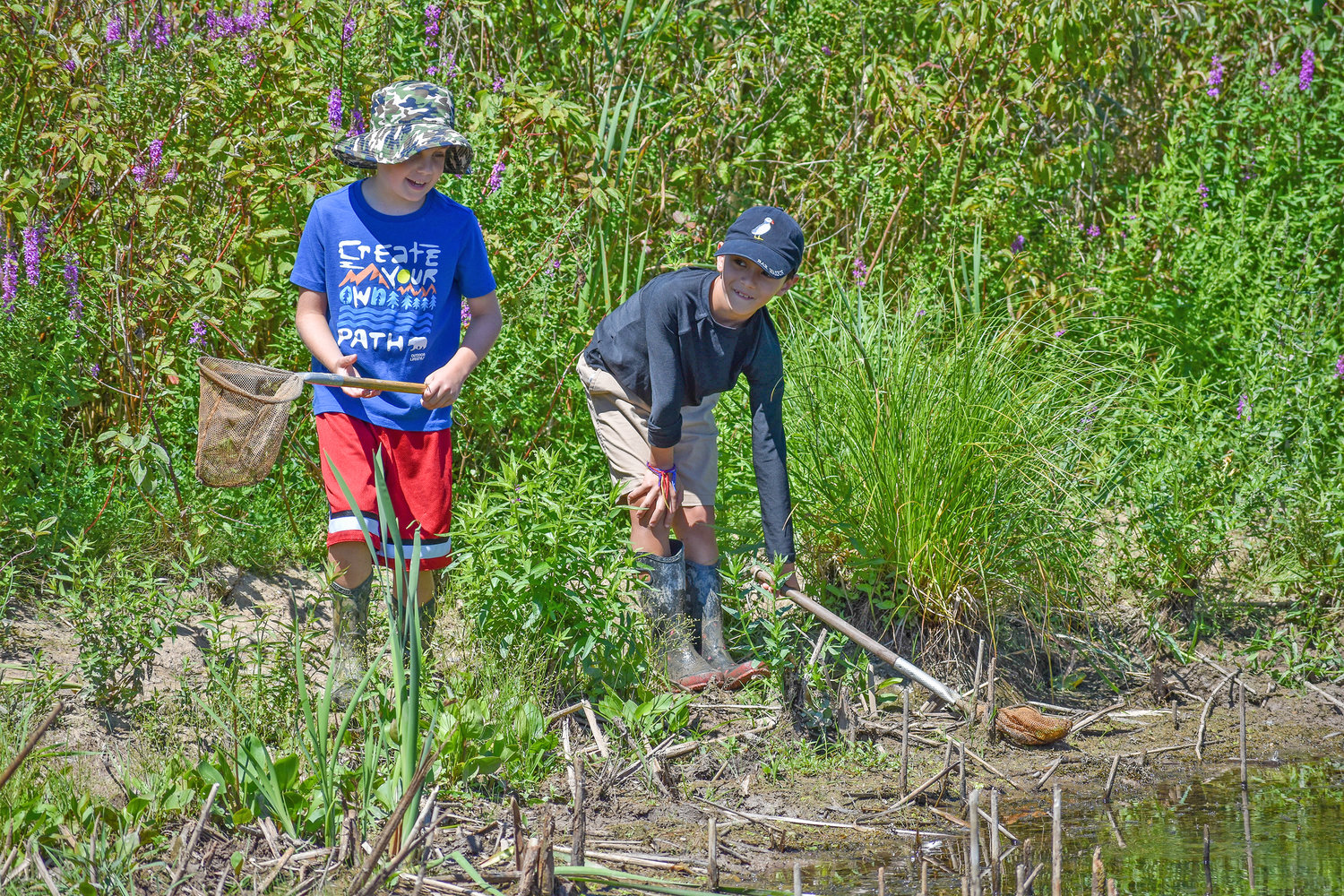 Ethan Lawrence (left), age seven, and Lochlan Fuller (right), age eight, explore the rim of the pond at the Great Swamp Conservancy.