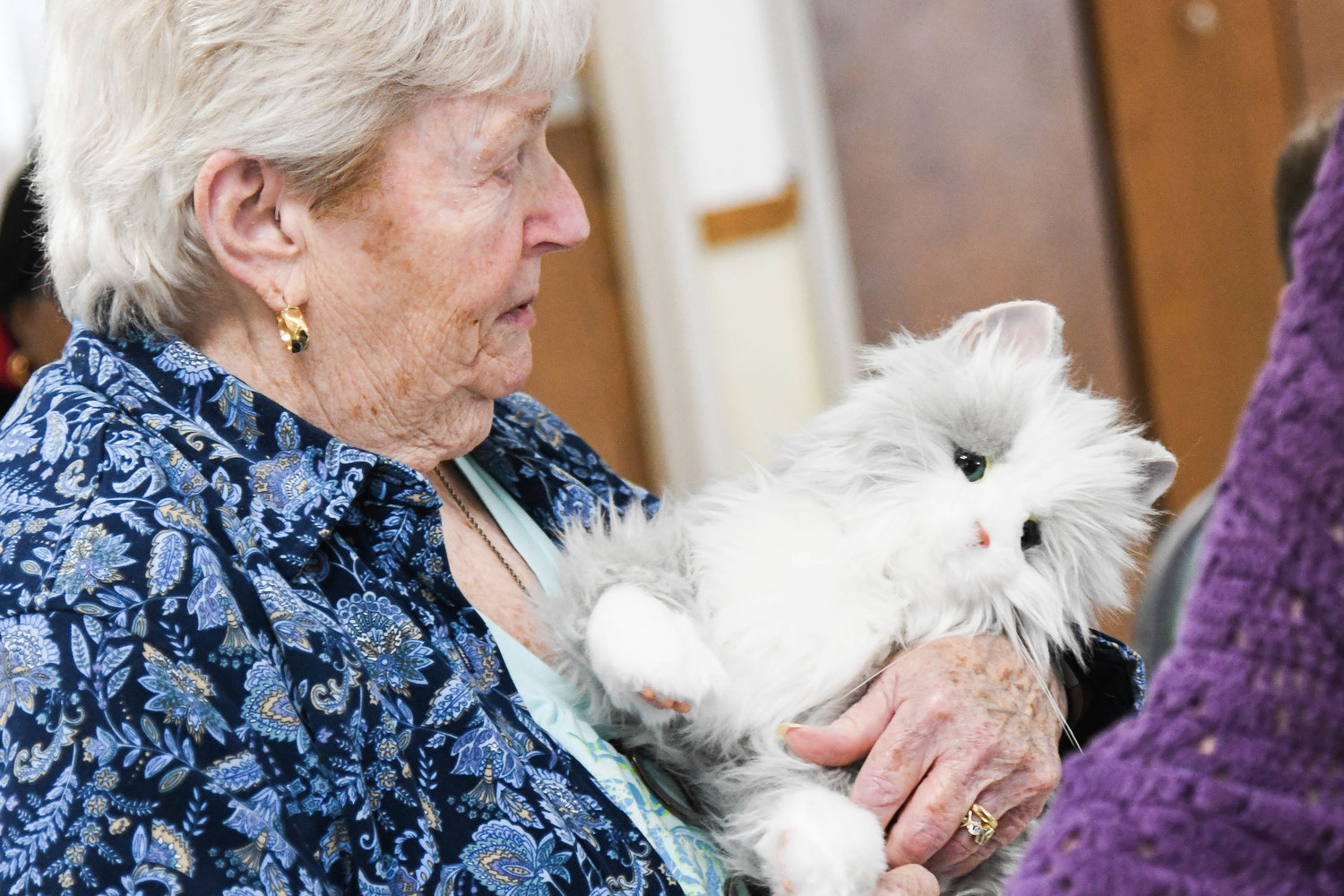 A member of the North Utica Senior Citizens Community Center holds an animatronic cat.
