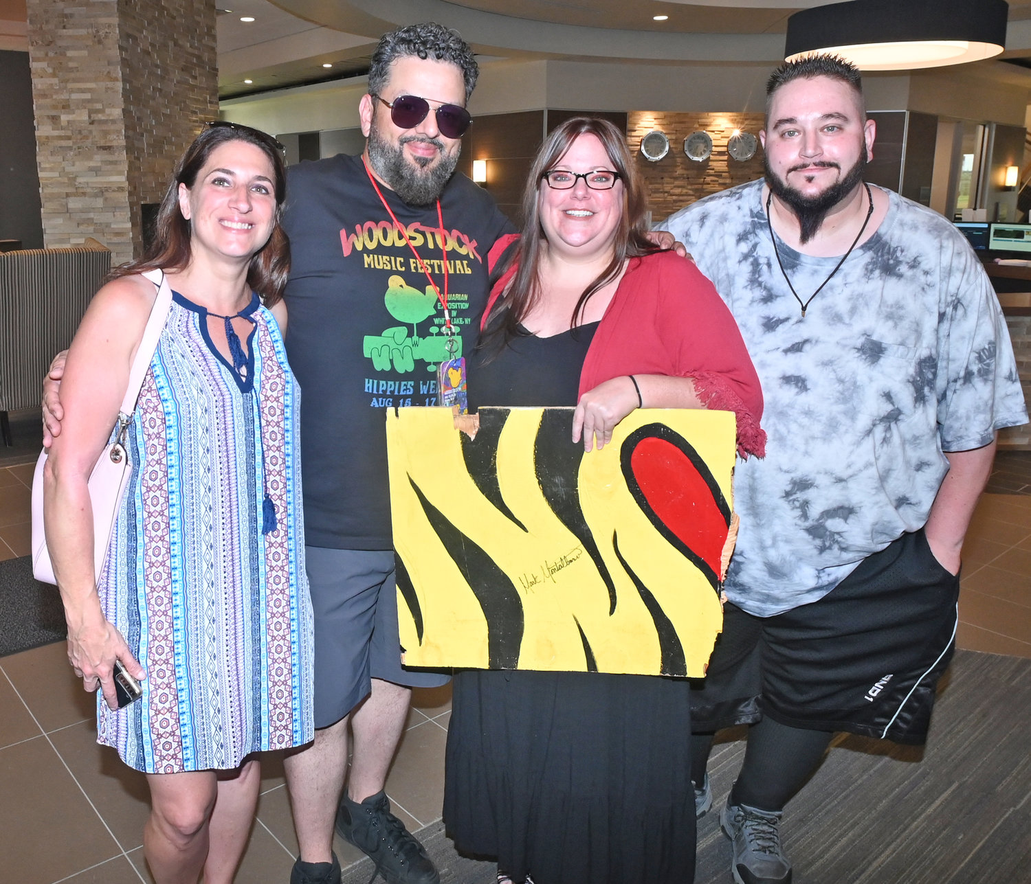 New friends, from left, Jennifer and Mark Montalbano, Maren Ondriska and Adam Hallenbeck with the hunk of painted plywood that brought the new friends together 23 years after Woodstock ‘99.