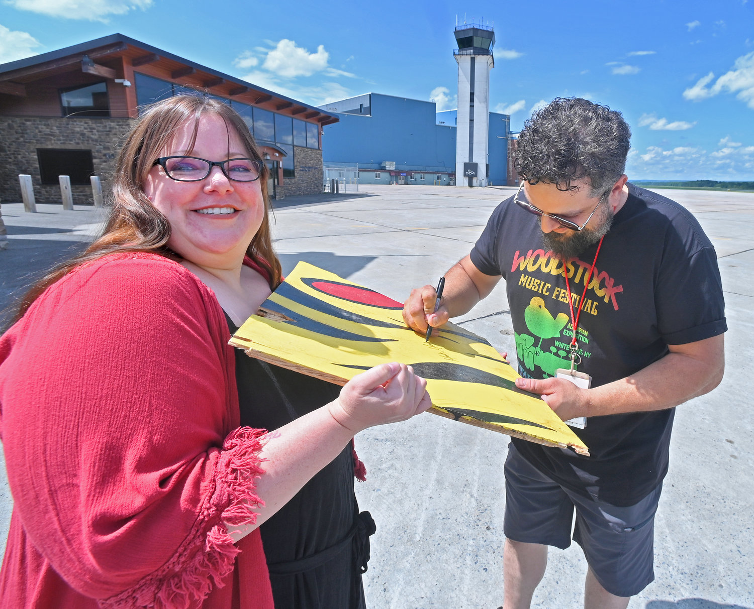 Maren Ondriska from Johnstown with Rome artist Mark Montalbano as he signs the 2x2 foot piece of Woodstock Girl he had painted 23 years ago for the Woodstock '99 music festival and was destroyed by concert goers along with all the other art that was created for the festival.