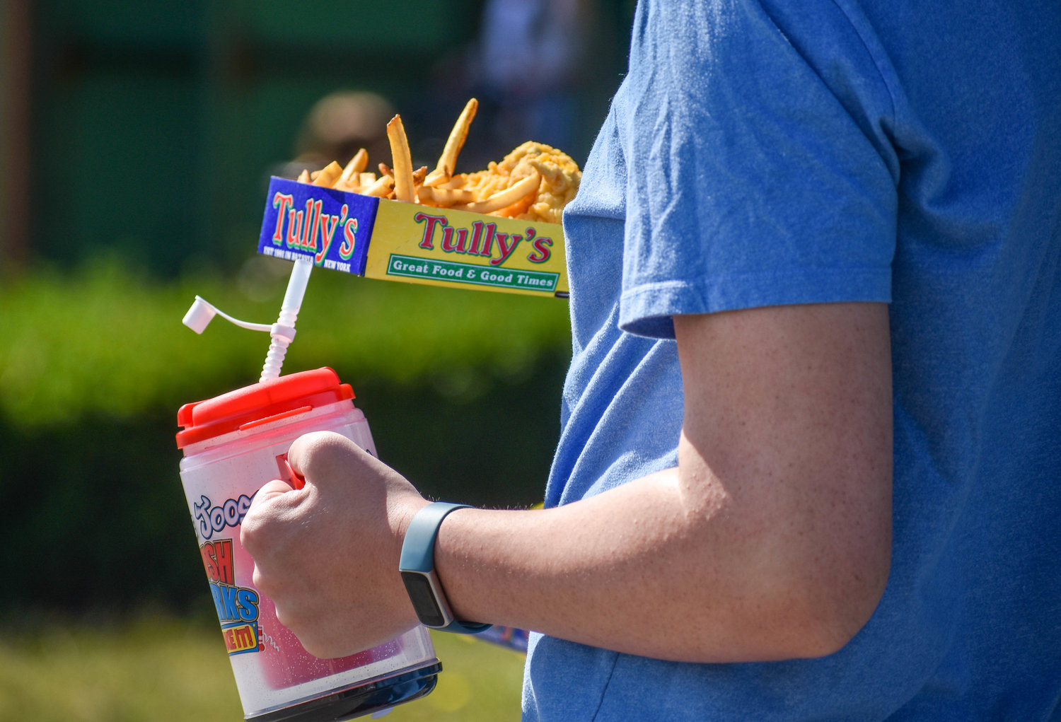 A fairgoer carries food from Tully’s, a favorite New York State Fair vendor serving its famous chicken tenders.