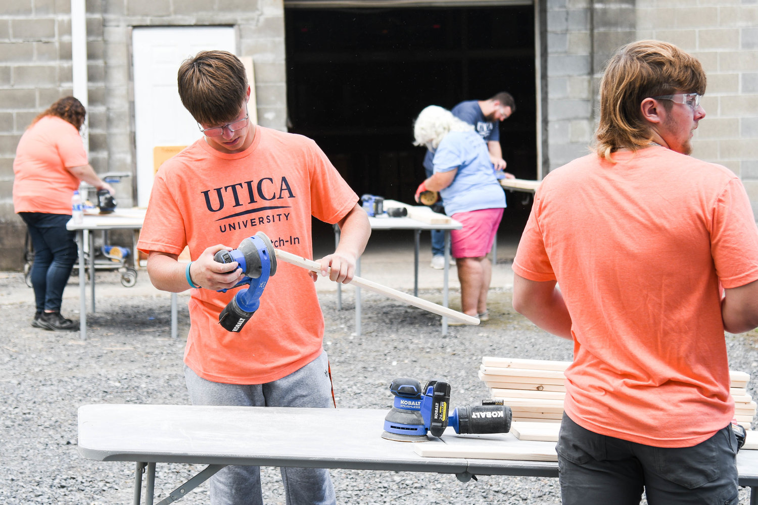 Utica University student Jake Wright, left center, sands down pieces of wood during the second annual Pioneer Pitch-In event on Thursday. Students were provided with the opportunity to aid and support Sleep in Heavenly Peace, a volunteer-based non-profit that builds beds for children in need. This group was primarily made up of new Construction Management majors, and they really got into the task at hand.