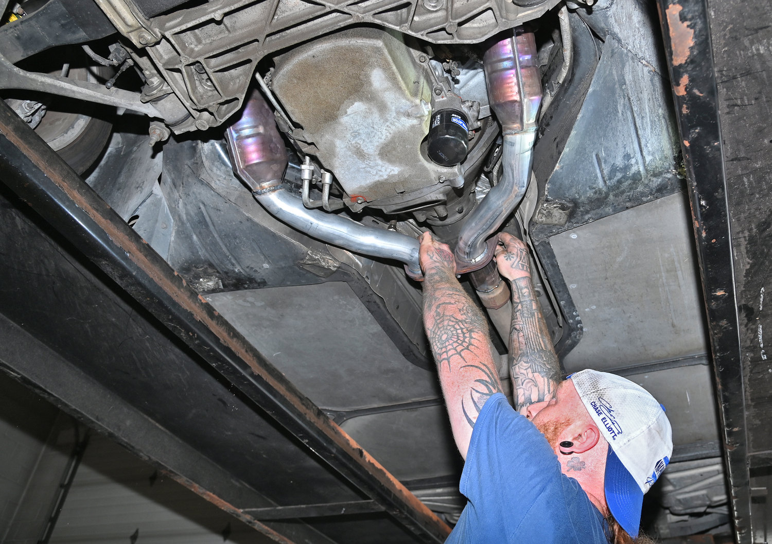 Premo Automotive mechanic Justin Sykes secures the exhaust beyond the catalytic converters that have the bronzish sheen to them. Premo’s had just installed a new exhaust system including two new catalytic converters. Premo Automotive is at 176 Black River Blvd N., Rome.