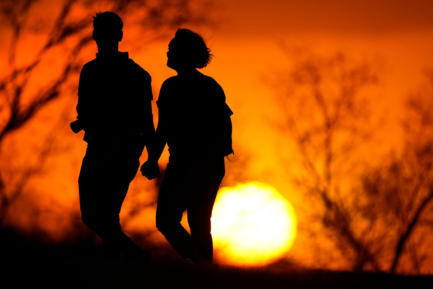 FILE - In this March 10, 2021 file photo, a couple walks through a park at sunset in Kansas City, Mo. U.S. life expectancy dropped for two consecutive years in 2020 and 2021, marking the first such trend since the early 1920s, according to a new government report. (AP Photo/Charlie Riedel, File)