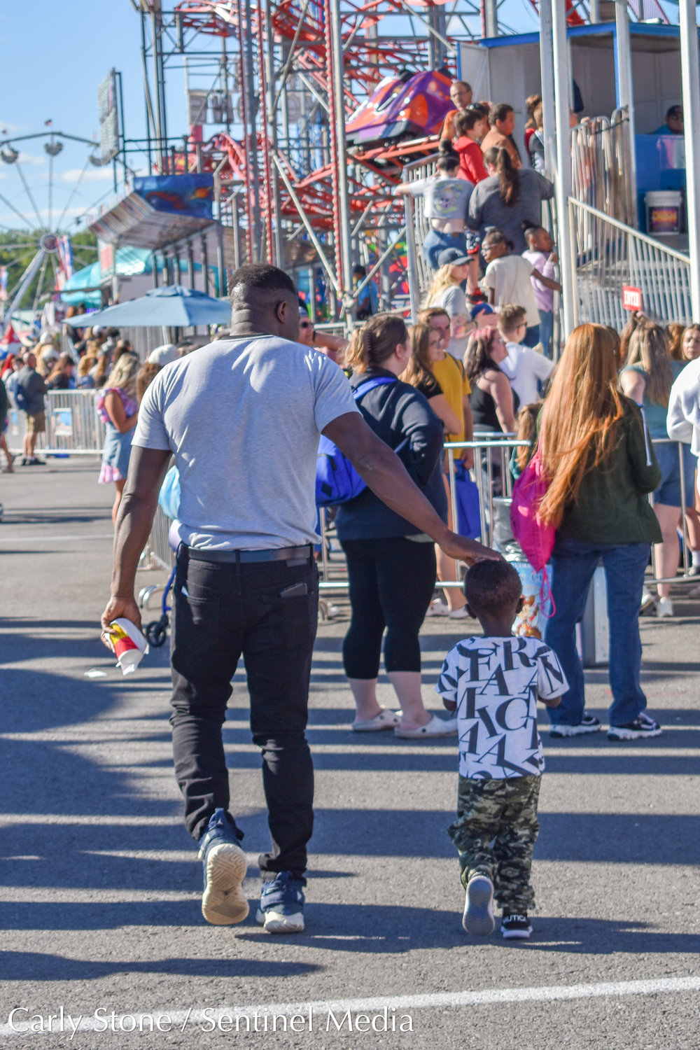 Flashing lights and bright colors adorned the state fair midway. These attendees, young and old, were passing by a ride called "Himalaya" where loud music is part of its allure.
