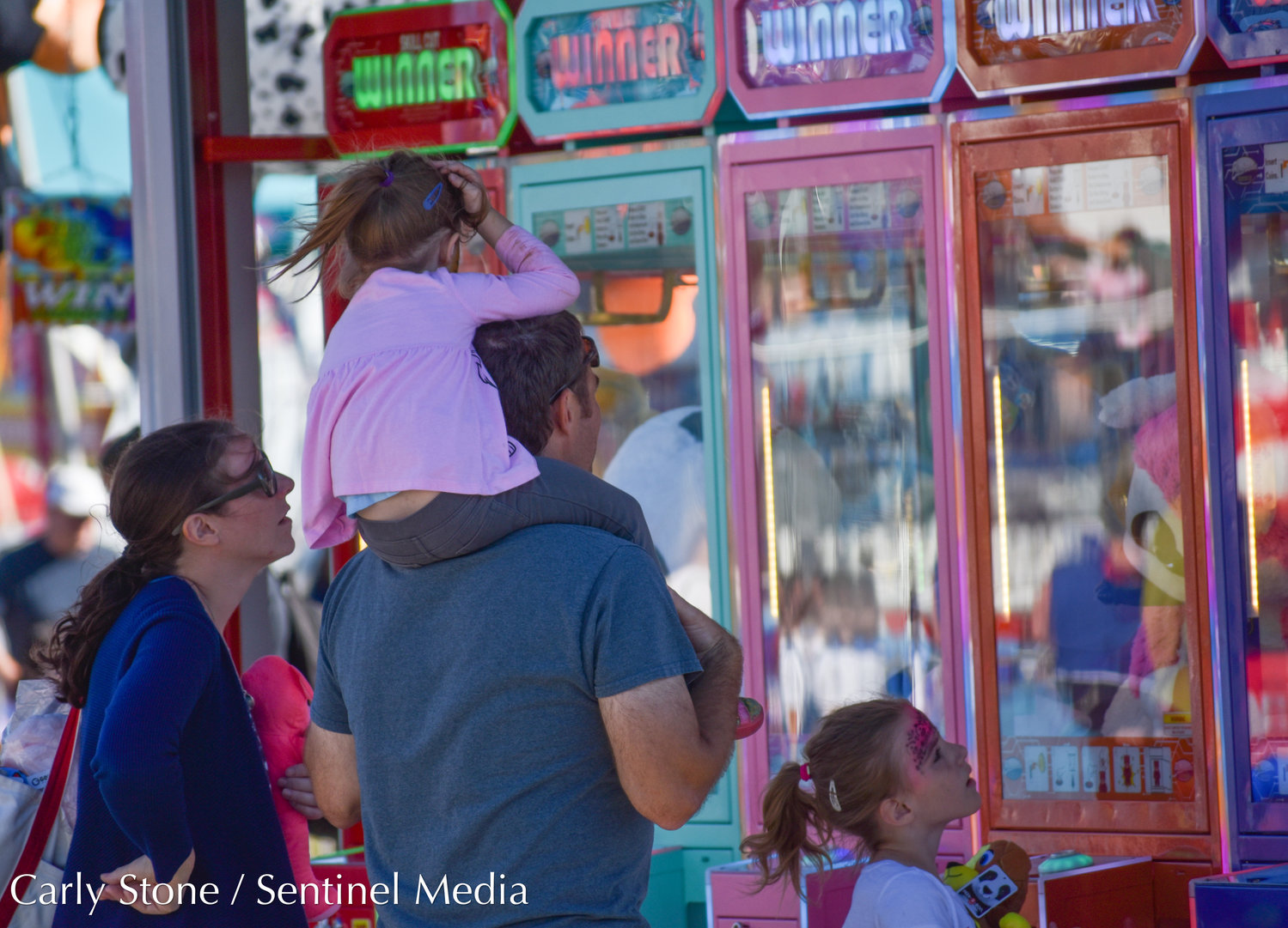 Claw machines and other tests of skill entertain people on the fair midway.
