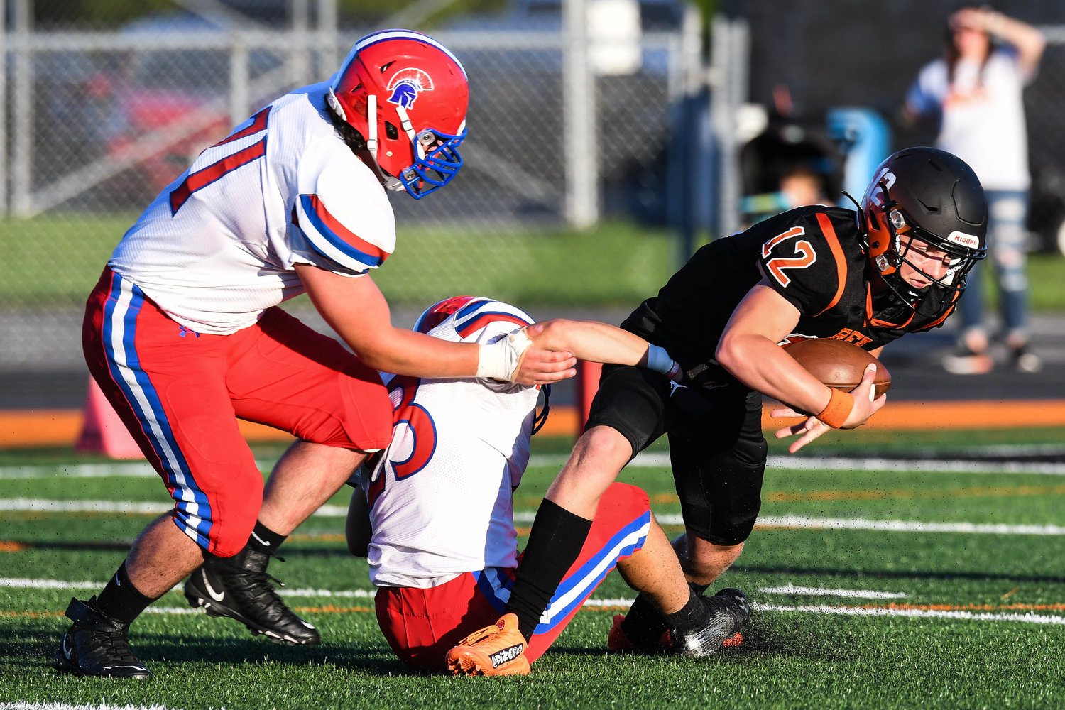 Rome Free Academy quarterback Evan Carlson-Stephenson is sacked by New Hartford's Nick Perrotta, center, and Michael Graziano during the game on Friday at RFA Stadium. New Hartford won 52-26 in both teams' first game of the season.