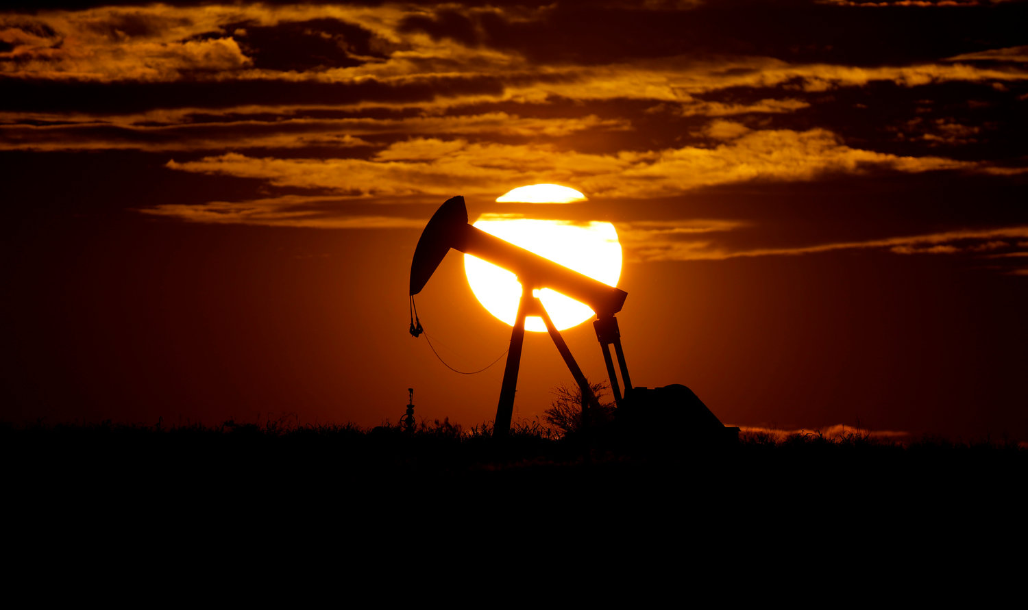 The sun sets behind an idle pump jack near Karnes City, USA, April 8, 2020. Oil prices are sagging amid fears of recessions across the globe. OPEC and allied countries are weighing what to do about that when they meet online Thursday, Sept. 8, 2022. High oil prices were a bonanza for countries like Saudi Arabia over the summer, but now they're well off those highs. Saudi Arabia's oil minister has even said the group known as OPEC+ could cut production at any time.
