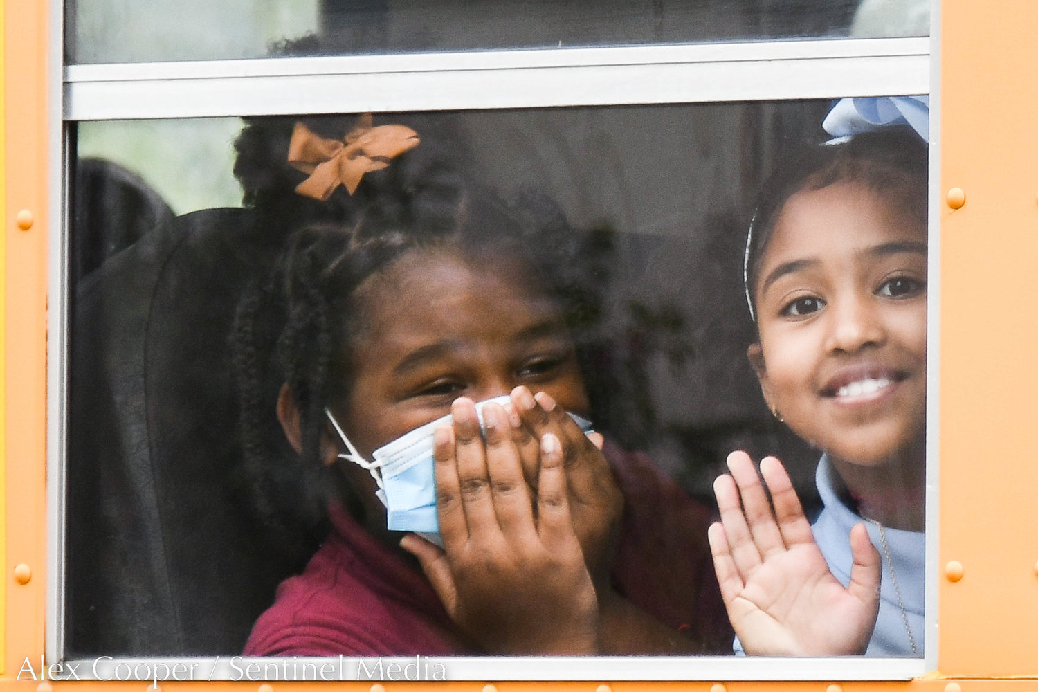 Two young students wave from the bus window during the first day back to school at Utica Academy of Science Elementary School on Tuesday in Frankfort.