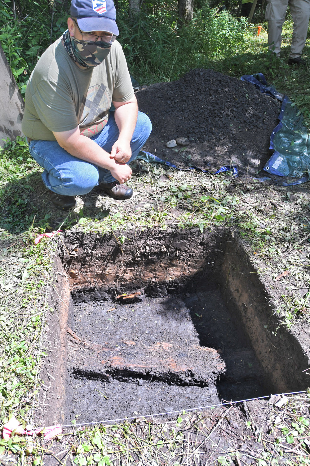 Brian Grills director of the Public Archaeology Facility at Binghamton Universtiy kneels next to a timber that was revealed during the dig. They found a smushed musket ball in the timber.