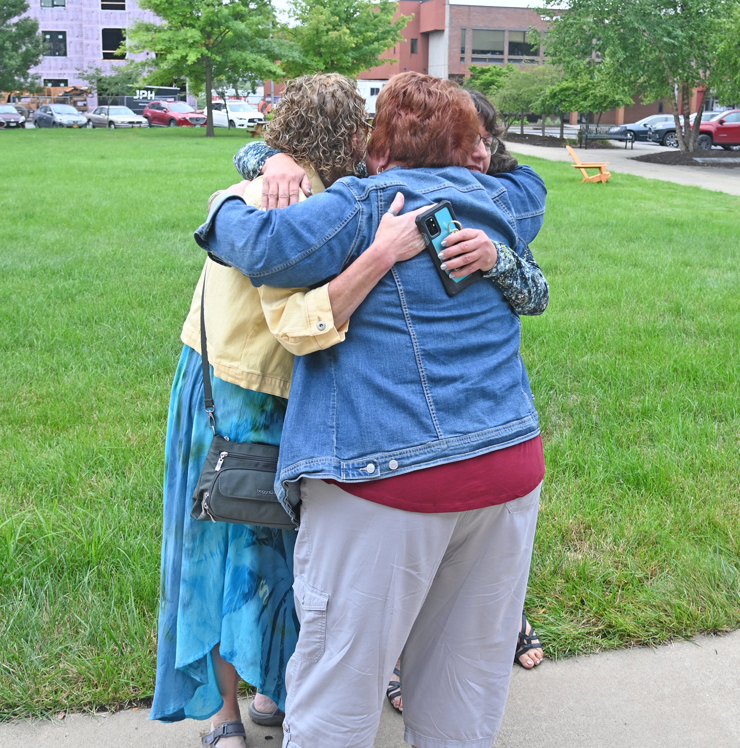 Lisa Davis, Judy Riker, and Shari Bujold share a hug after raising the brain aneurysm awareness flag at Rome City Hall on Friday. All three women had a loved one pass away because of an aneurysm.
