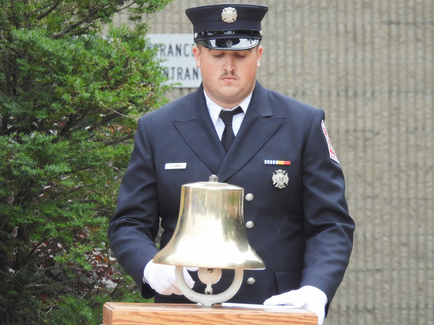 Oneida Firefighter Andrew Cooney rings the bell, recognizing the first, second, and third plane strikes and the crash of United Airlines Flight 93 at the city of Oneida's 9/11 Remembrance Ceremony on Sunday.