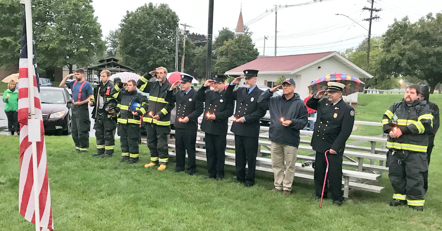 Sherrill-Kenwood Volunteer Fire Department members hold candles and salute the flag Sunday during the annual 9/11 Remembrance Ceremony in Sherrill.