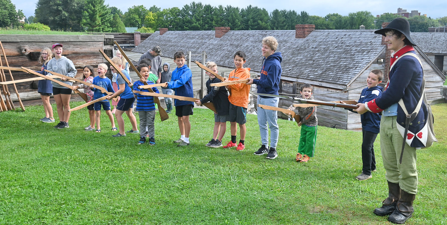 A group of homeschooled children visiting Fort Stanwix Wednesday yell "Huzzah" with 3rd NY Regiment Private Elijah Braun during a demonstration of a musket drill.