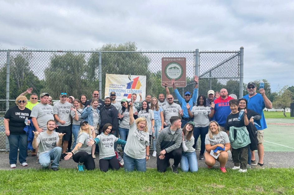 Members of the United Way of the Mohawk Valley’s Emerging Leaders United group celebrate after clearing debris along the sidewalks and streets and open space in the Liberty Gardens, Gansevoort Elementary School, and Steven’s Field Playground areas on Saturday.