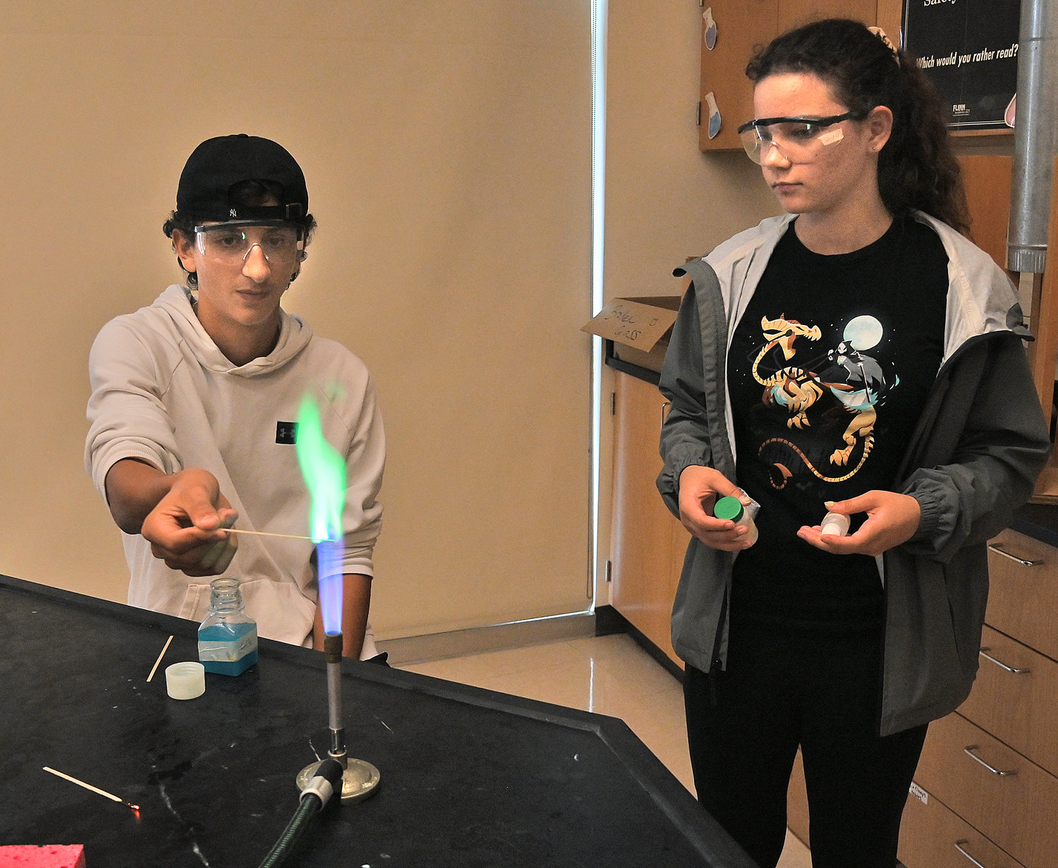 New Hartford Senior High School science students, from left, Gianni Trevisani and Meredith Porter, both juniors, make colorful flames Monday.