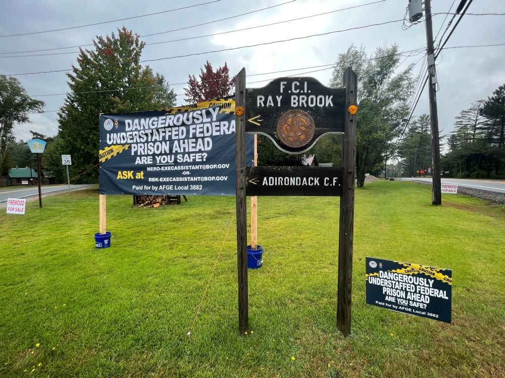 The new 6 x 12 foot sign was installed recently near the sign pointing  towards the federal prison in Ray Brook and the Adirondack Correctional Facility, a state prison.