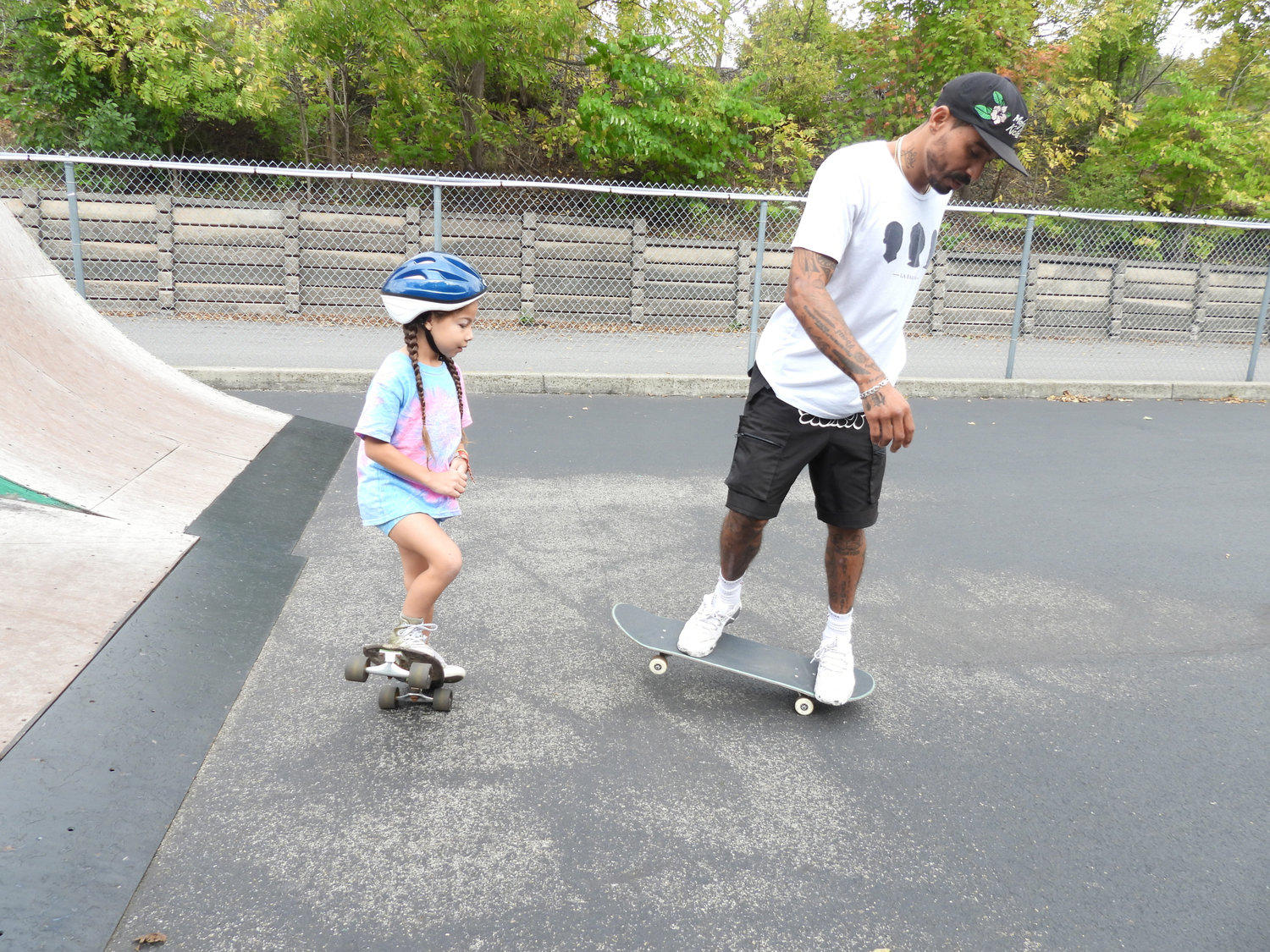 Emanuel "Manny" Santiago teaches a young skater the proper form to turn her board at Lenox Skate Park on Saturday, Sept. 24