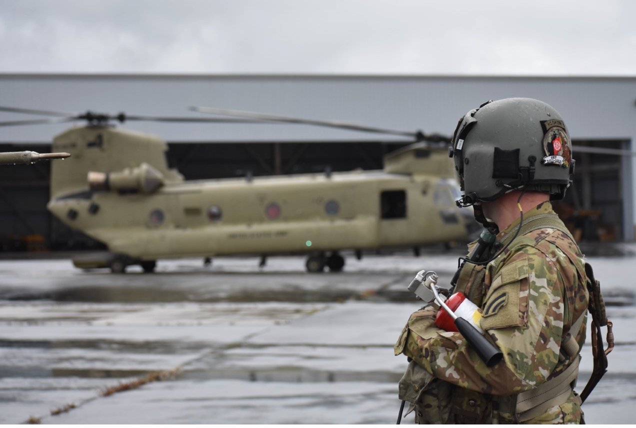 A New York Army National Guard Soldier assigned to B Company of the 3rd Battalion, 126th Aviation Regiment watches as a CH-47 prepares to start engines on Wednesday, Sept. 28, at Frederick Douglas Greater Rochester International Airport en route to Florida to assist in hurricane response missions.