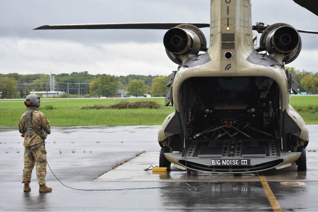 A New York Army National Guard Soldier assigned to B Company of the 3rd Battalion, 126th Aviation Regiment watches as a CH-47F prepares to start engines on Wednesday, Sept. 28, 2022 at Frederick Douglas Greater Rochester International Airport en route to Florida to assist in hurricane response missions. At the direction of Governor Kathy Hochul, 11 Soldiers and two CH-47F Chinook heavy lift helicopters were dispatched to Florida. ( U.S. Air National Guard photo by 1st Lt. Jason Carr):