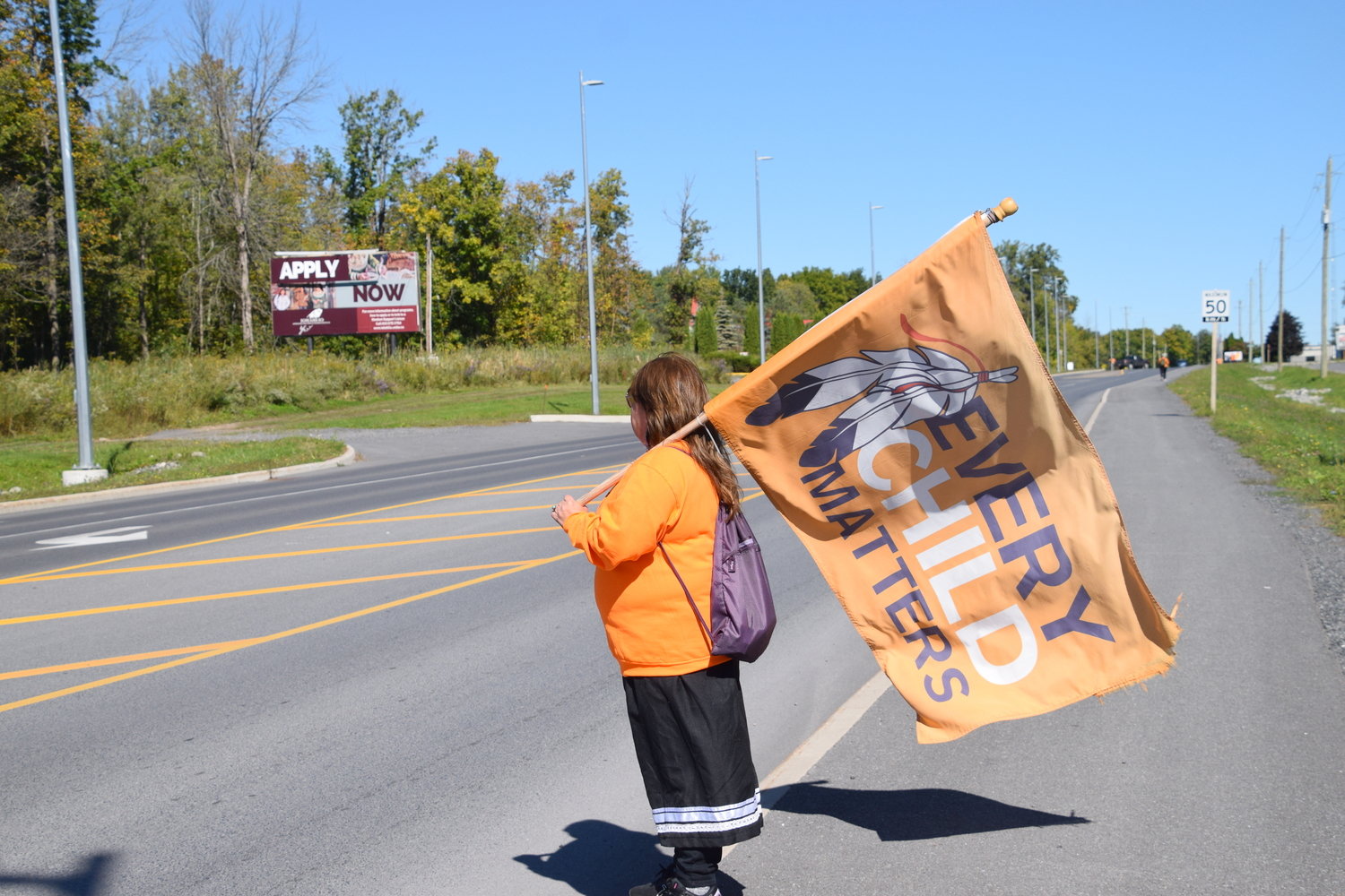 A protester carries a flag that reads, “Every Child Matters,” while marching from Akwesasne to Trinity Anglican Church in Ontario to call for the release of all records related to the Mohawk Institute residential school.