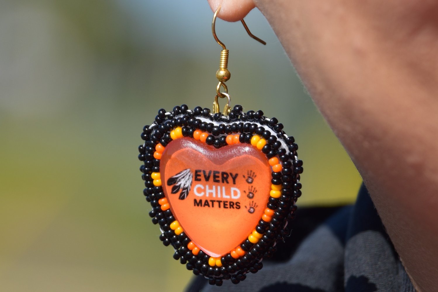 Heather George wears a pair of earrings with the slogan “Every Child Matters” while marching with Mohawk Institute survivors and their families for access to Anglican Church records.