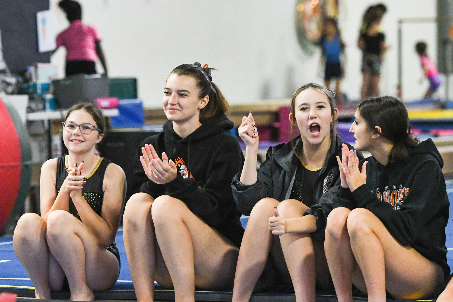 Rome Free Academy gymnastics team members cheer on a teammate competing in bars during competition on Thursday at Valley Gymnastics in Utica.