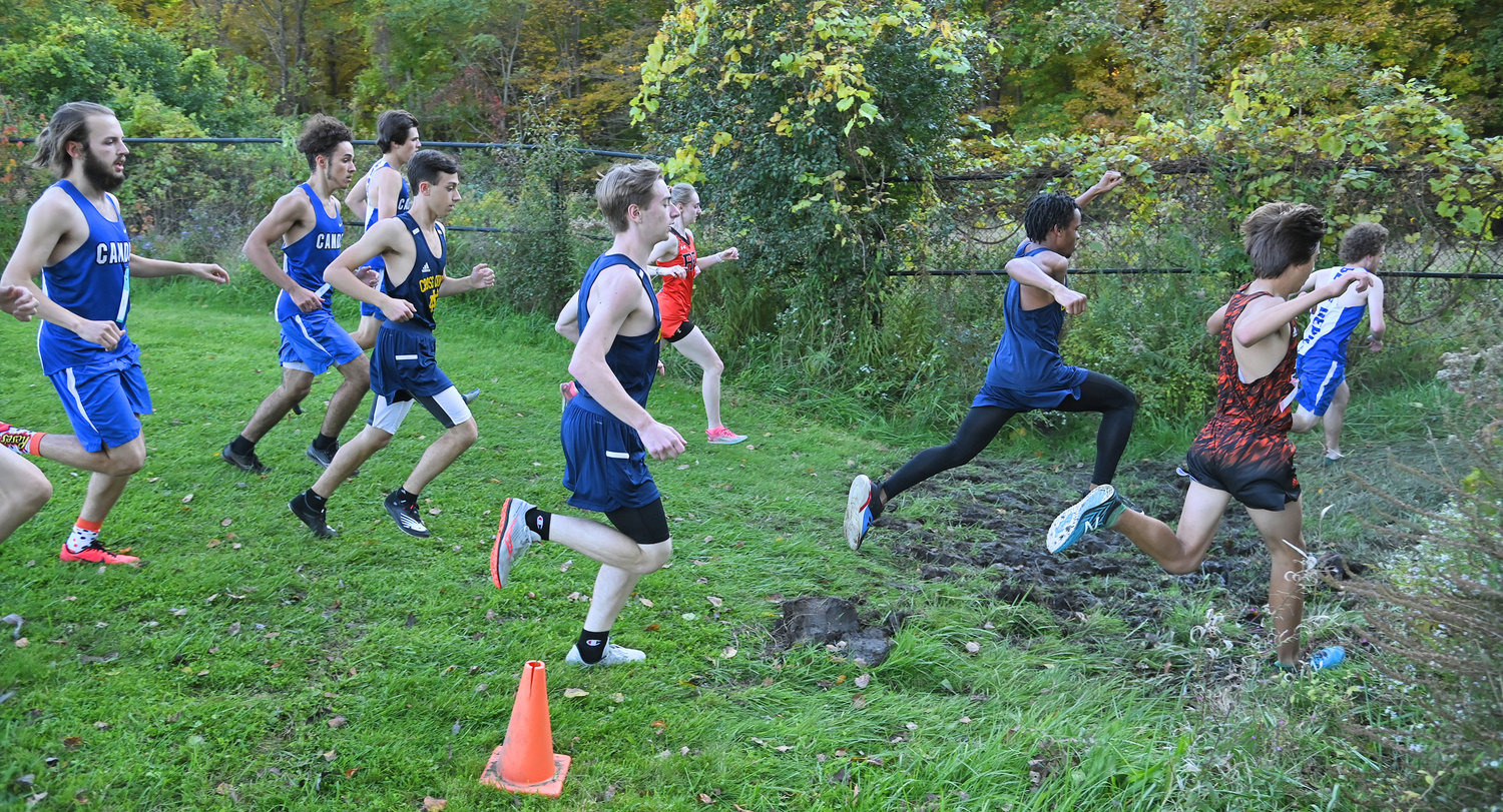 Varsity cross country runners cross a muddy patch on the way into the woods Tuesday, October 11, at the Rome Free Academy course.