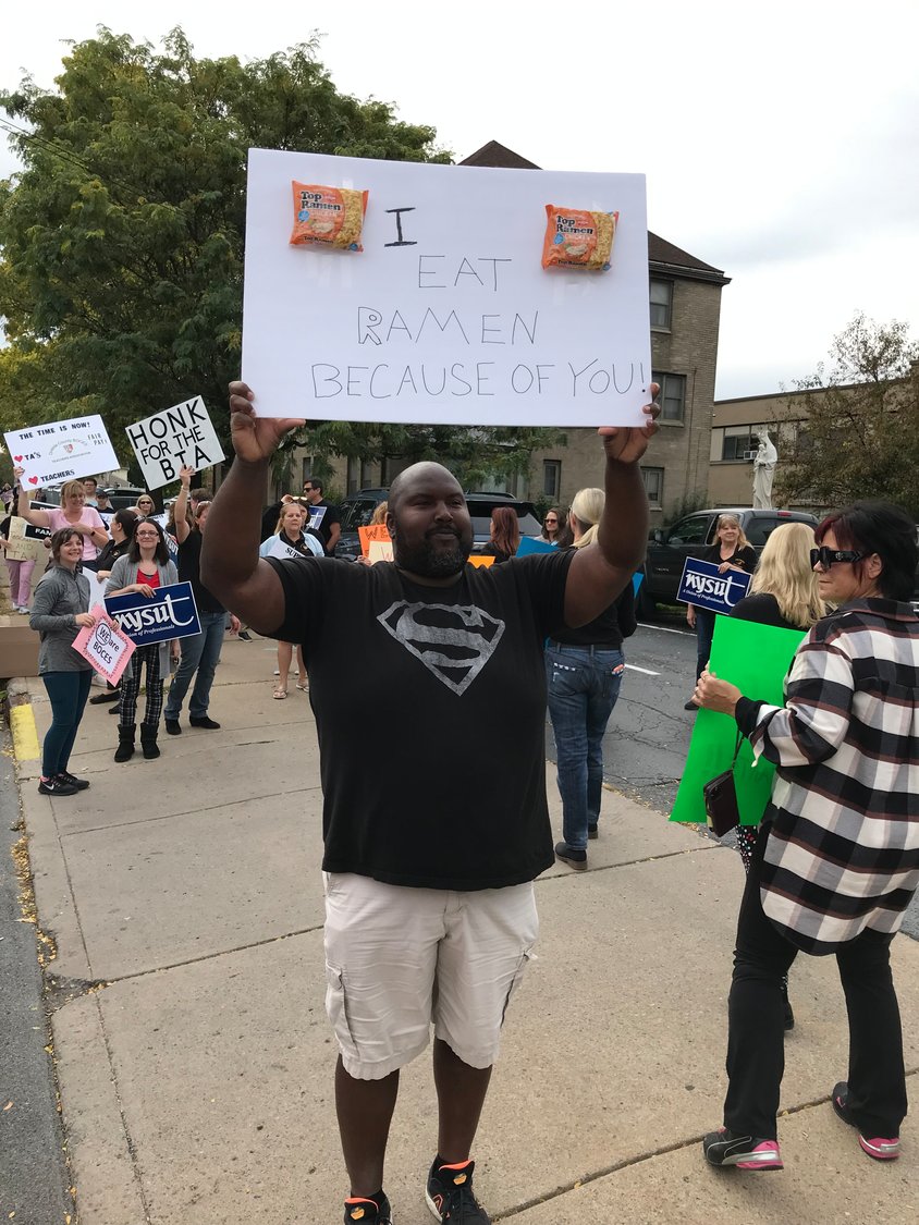 Teaching assistant Oscar Grimes holds a sign that reads "I eat Ramen because of you" as Oneida County BOCES Teachers Association members and supporters picketed Wednesday outside the meeting place of the BOCES Cooperative Board at Middle Settlement Academy in Utica.