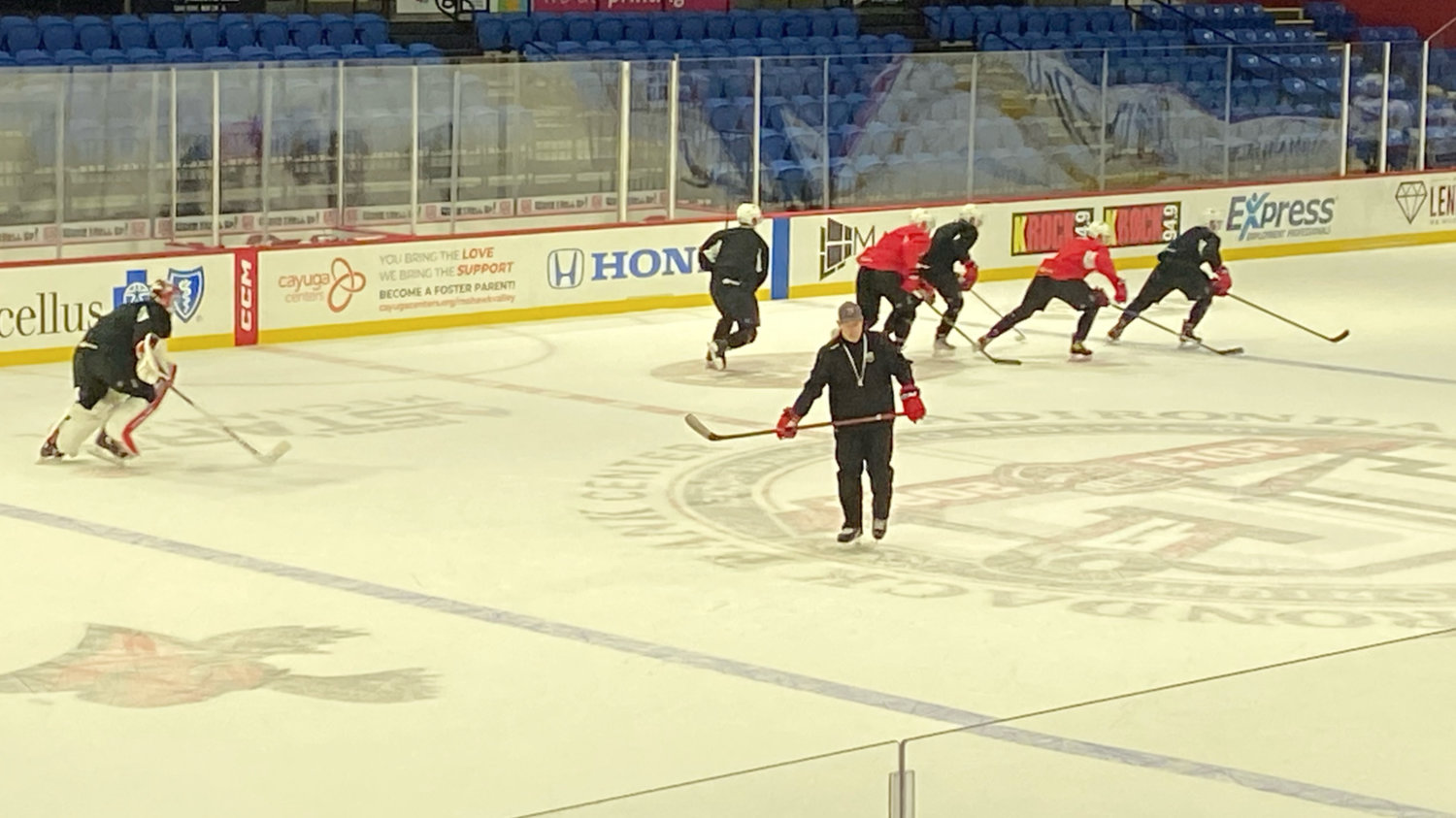 Utica Comets coach Kevin Dineen skates in front of players going through conditioning drills at Tuesday's practice at the Adirondack Bank Center in Utica.
