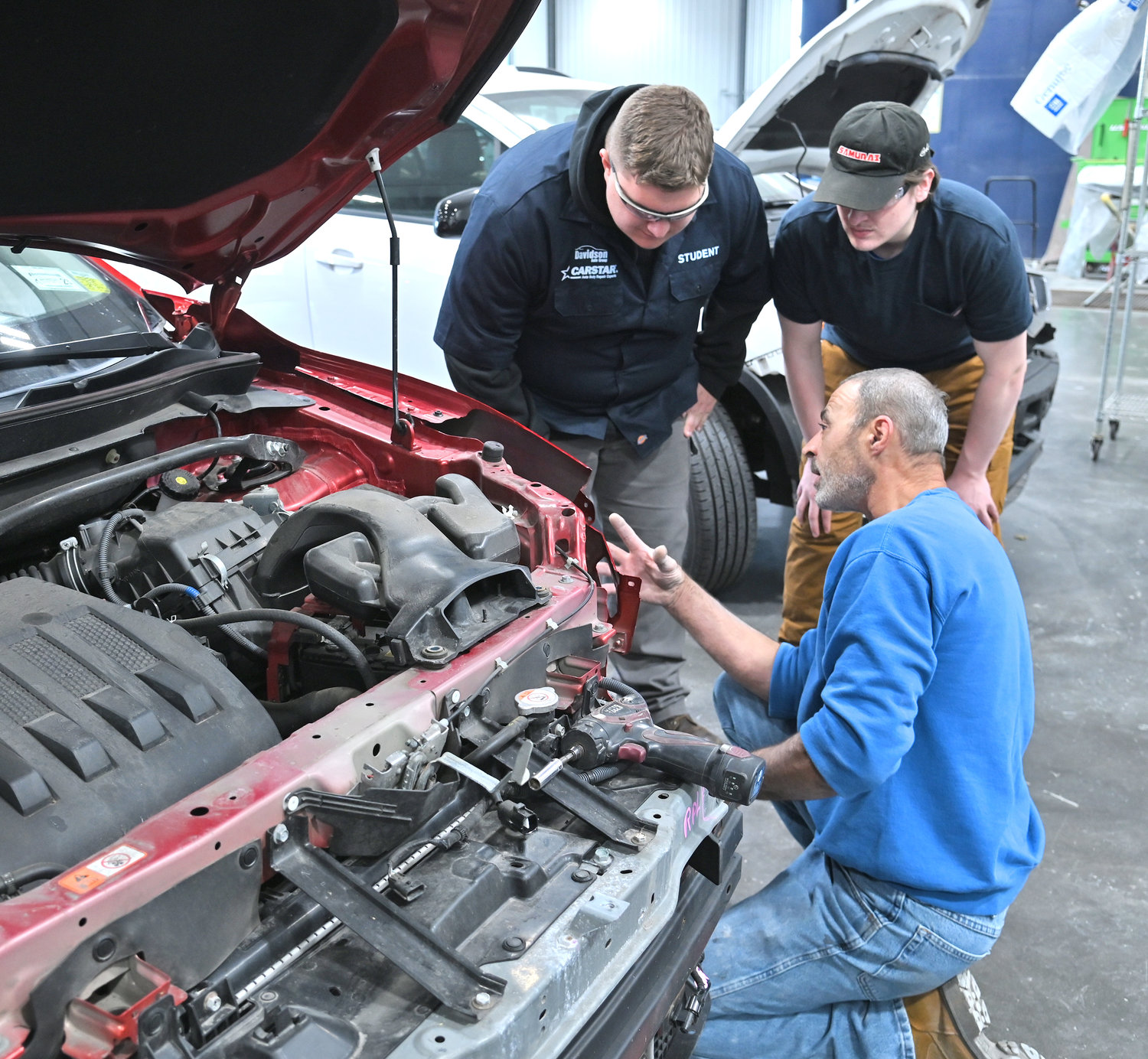 Duane Roser, a body technician for 37 years, shows Madison-Oneida BOCES students Trevor Marsden of Camden and Tobiah Garcia of VVS the process as he repairs a car Oct. 21 at the CARSTAR Davidson Collision facility in Rome.