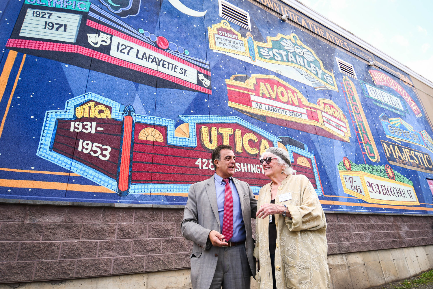 Utica Mayor Robert Palmieri talks with Lynne Mishalanie during a celebration that marked the completion of a large mural painted on the Player’s Theatre north wall on Tuesday, Oct. 25, in downtown Utica. The mural features recreations of nine downtown Utica movie theater marquees from the early 1900s to the mid ‘60s, and was painted by Maria Vallese of Retro Sorrento.