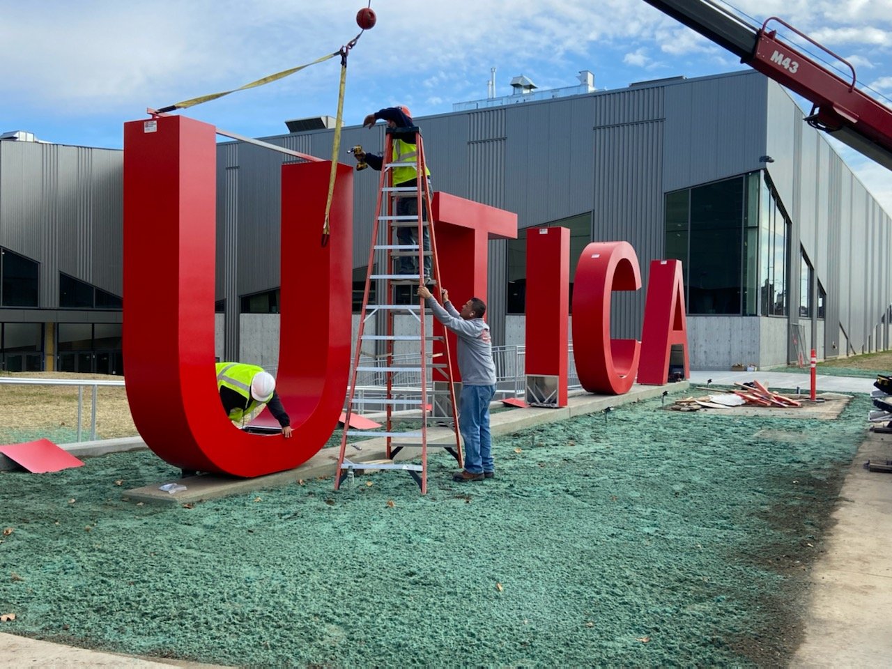 A crew puts the finishing touches on the letter “U” in a Utica sign as it is set to be hoisted into place at the Nexus Center facility in Utica.  Officials say the new multisport facility in downtown Utica is set to begin gameplay on Wednesday, Nov. 9.
