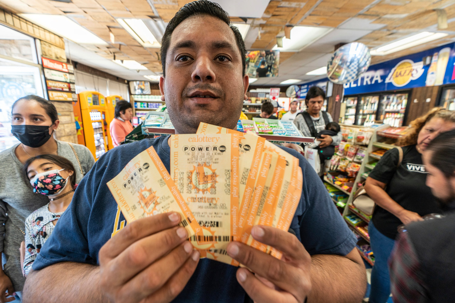 Hector Solis holds up lottery tickets purchased with his co-workers for the Saturday drawing of the Powerball lottery at the Bluebird Liquor store in Hawthorne, Calif., Saturday, Nov. 5, 2022.