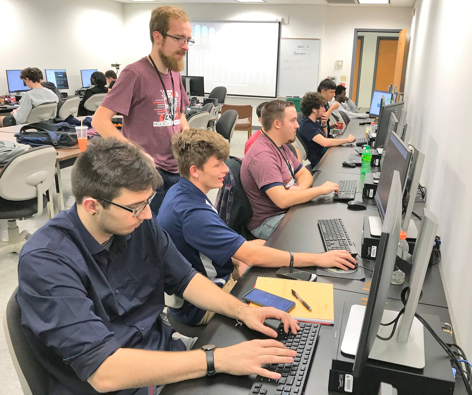 Facilitator Sean Drzewiecki, standing, offers guidance to college students participating in the CNY Hackathon Saturday at Mohawk Valley Community College in Utica.