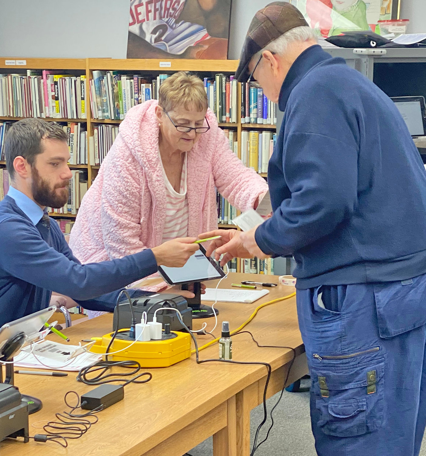 Adam Palmer, left, and Rose Koss, center, help to check in Oriskany resident John LaVoe on Tuesday at the Oriskany Public Library in Tuesday’s general election.