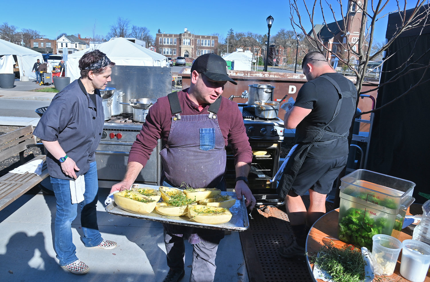Restuarant Impossible chef Brian Goodman transfers squash with Chef Tito Marino in black working at the stove. On the left is Michelle Willson of Camden who volunteered to help with preparation for the show on Nov. 9, 2022.