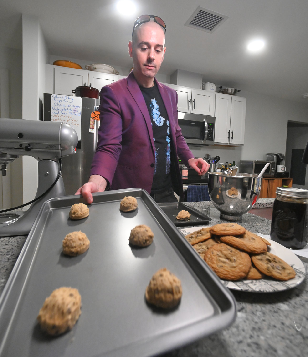 James Daino picks up a cookie sheet of his cookies to bake in the 350-degree oven Wednesday in his Rome kitchen.