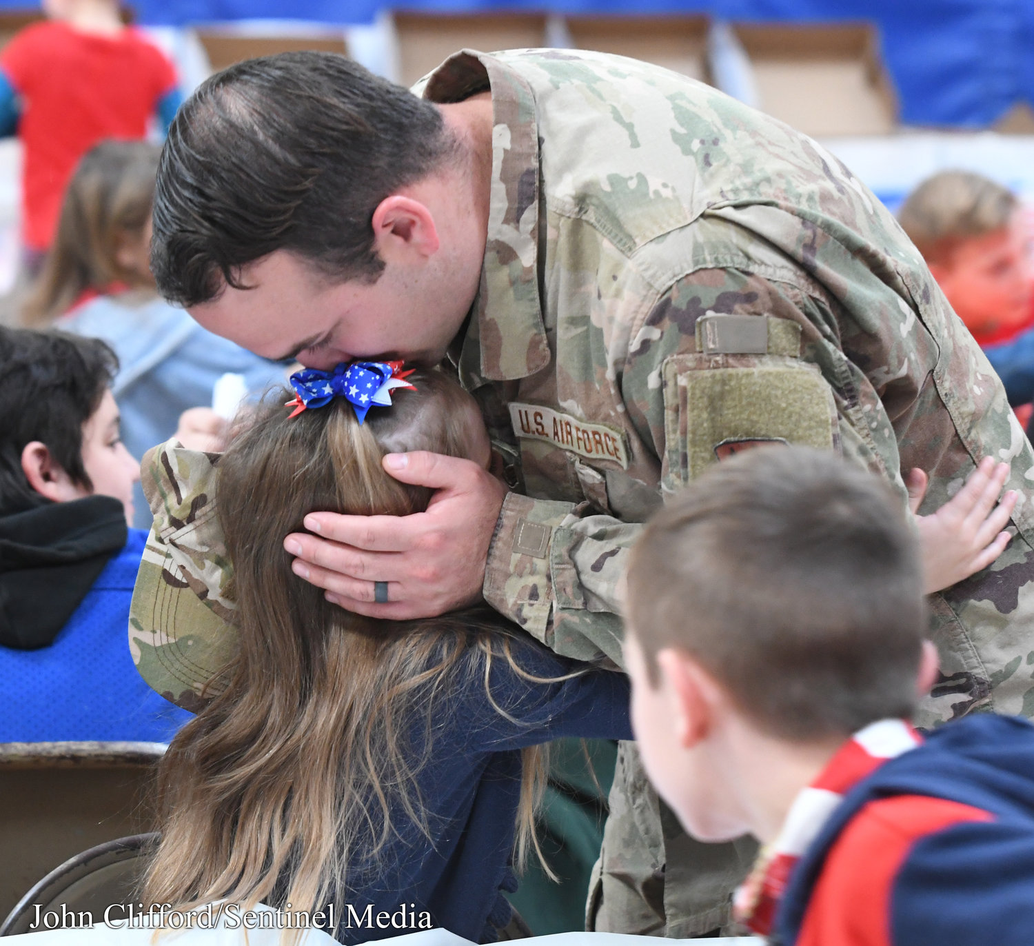 Air Force Staff SGT Sullivan Derrick kisses his daughter Maeve Derrick a kindergartener at Stokes Elementary School following the veterans day ceremony at the school Thursday, November 10, 2022.