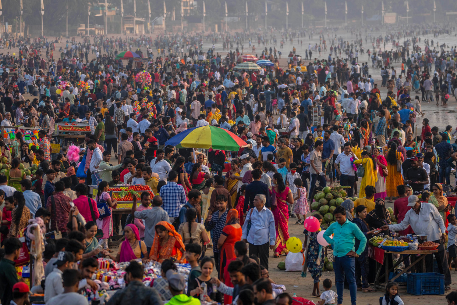 People crowd at the Juhu beach on the Arabian Sea coast in Mumbai, India, Sunday, Nov. 13, 2022. The 8 billionth baby on Earth is about to be born on a planet that is getting hotter. But experts in climate science and population both say the two issues aren't quite as connected as they seem. (AP Photo/Rafiq Maqbool)