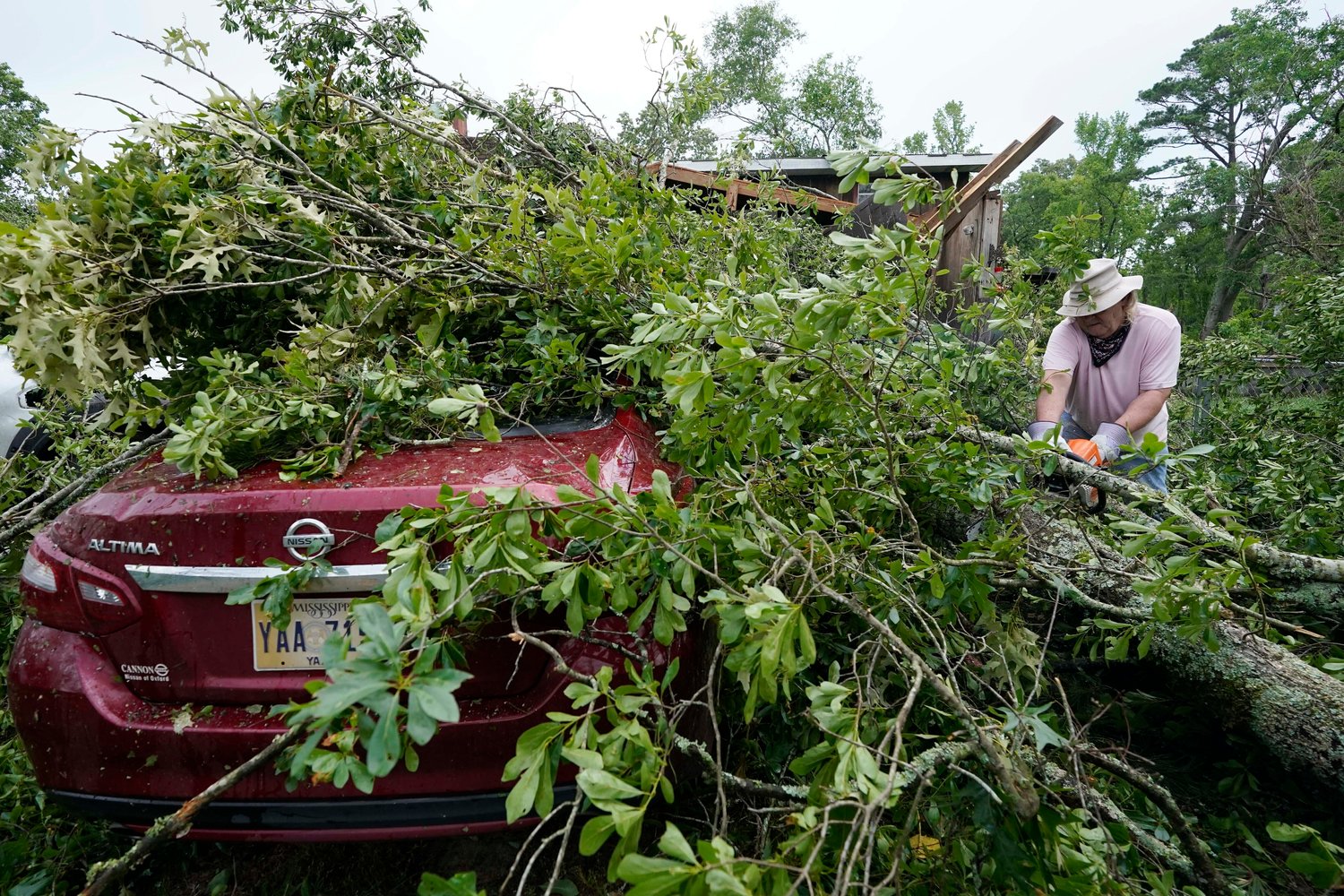 FILE - Span McGinty uses his chain saw to cut fallen tree limbs from a tornado-damaged vehicle at his brother's house in Yazoo County, Miss., on May 3, 2021. 90% of counties in the United States experienced a weather-related disaster between 2011-2021, according to a report published on Wednesday, Nov. 16, 2022. Over 300 million people ‚Äî 93% of the country‚Äôs population ‚Äî live in those counties. (AP Photo/Rogelio V. Solis, File)