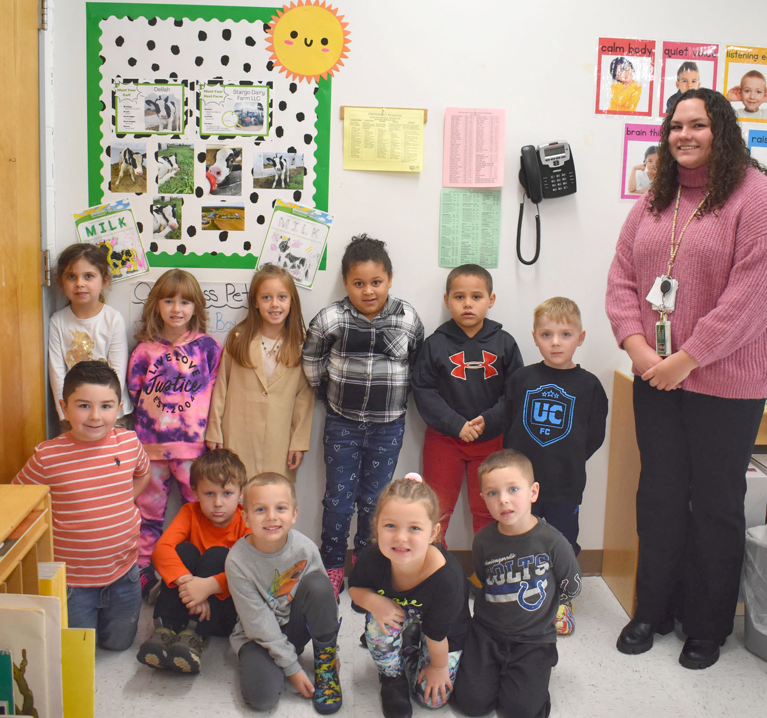 Herkimer Central School District kindergarten teacher Amanda Johnson’s class poses by a display of photos showing a cow named Delilah that the class adopted.