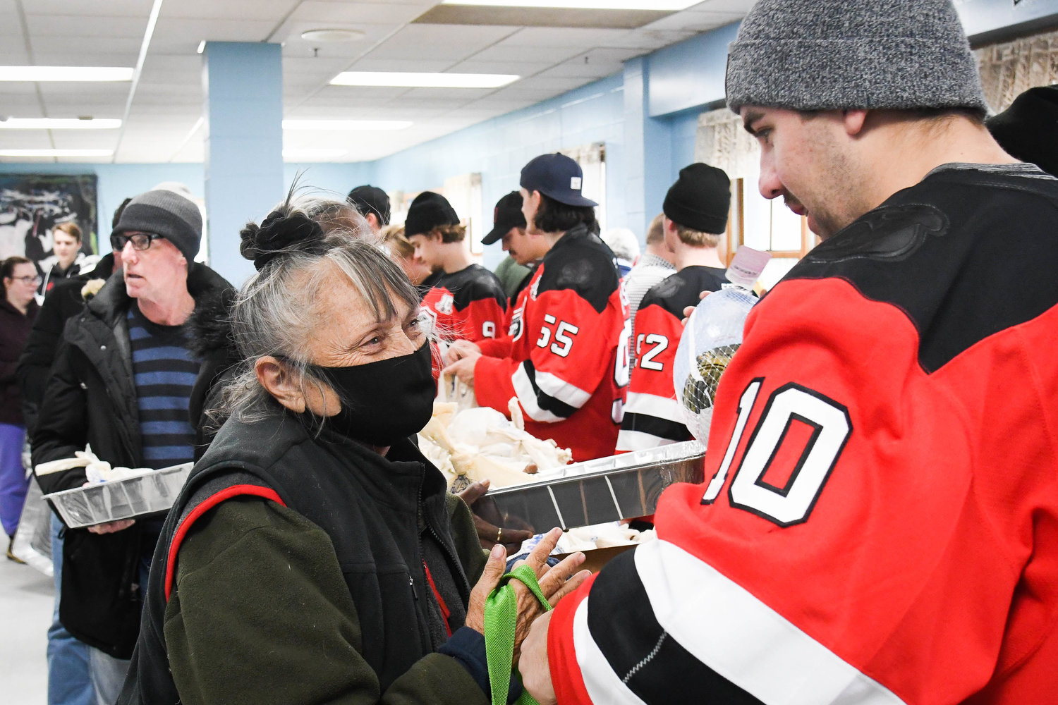 Utica Comets player Jack Dugan hands a woman a turkey on Tuesday at the Utica Rescue Mission on Rutger Street.