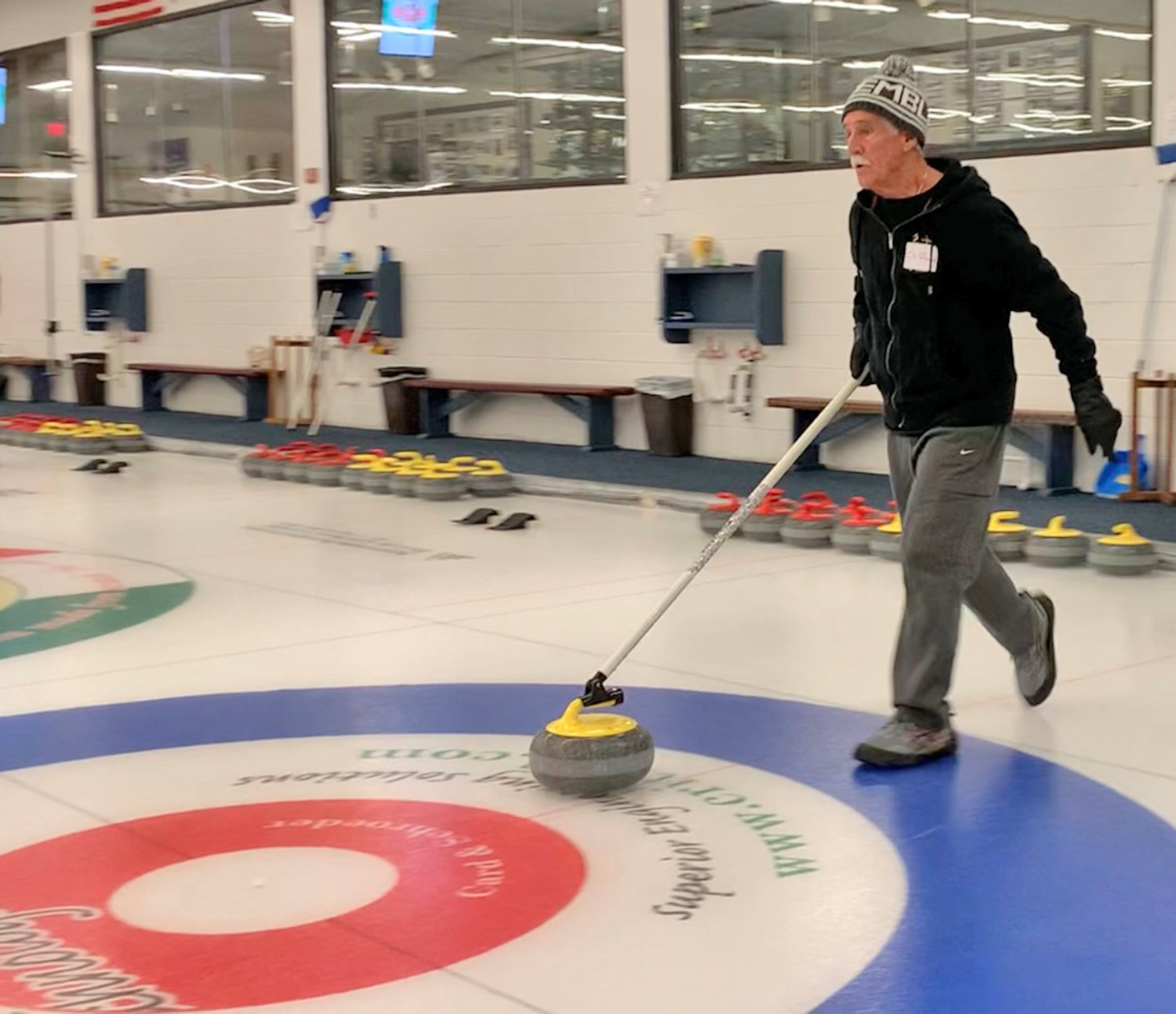 Clifford Crandall Jr. delivers a curling stone from the standing position at Utica Curling Club.