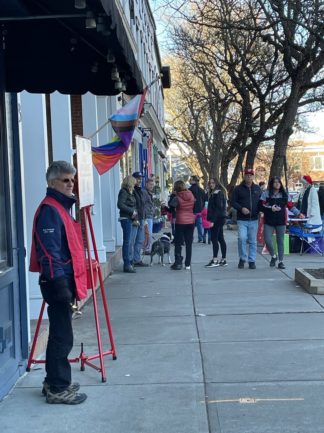 Shoppers stroll down West Park Row in Clinton in between visiting local shops during Small Business Saturday as a volunteer rings the bell for the Salvation Army Red Kettle Campaign.