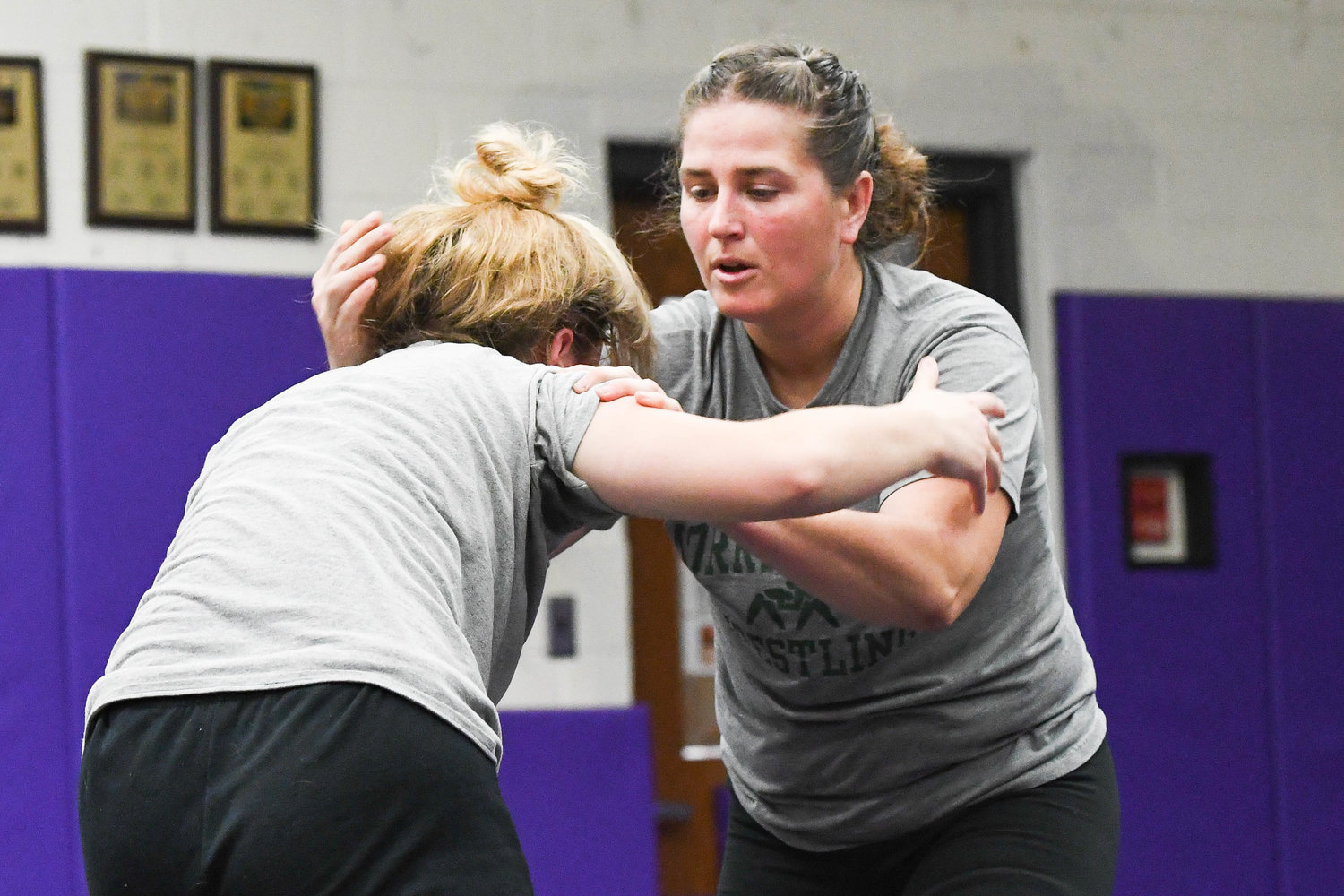 Holland Patent head coach Samantha Doxstader, right, demonstrates a move on Stephanie Grocholski during wrestling practice on Monday at Holland Patent High School.